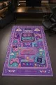 Çok renkli oyuncu halısında girl gamer yazısı, oyun kumandası, kulaklık, klavye ve kalp motifleri görülür